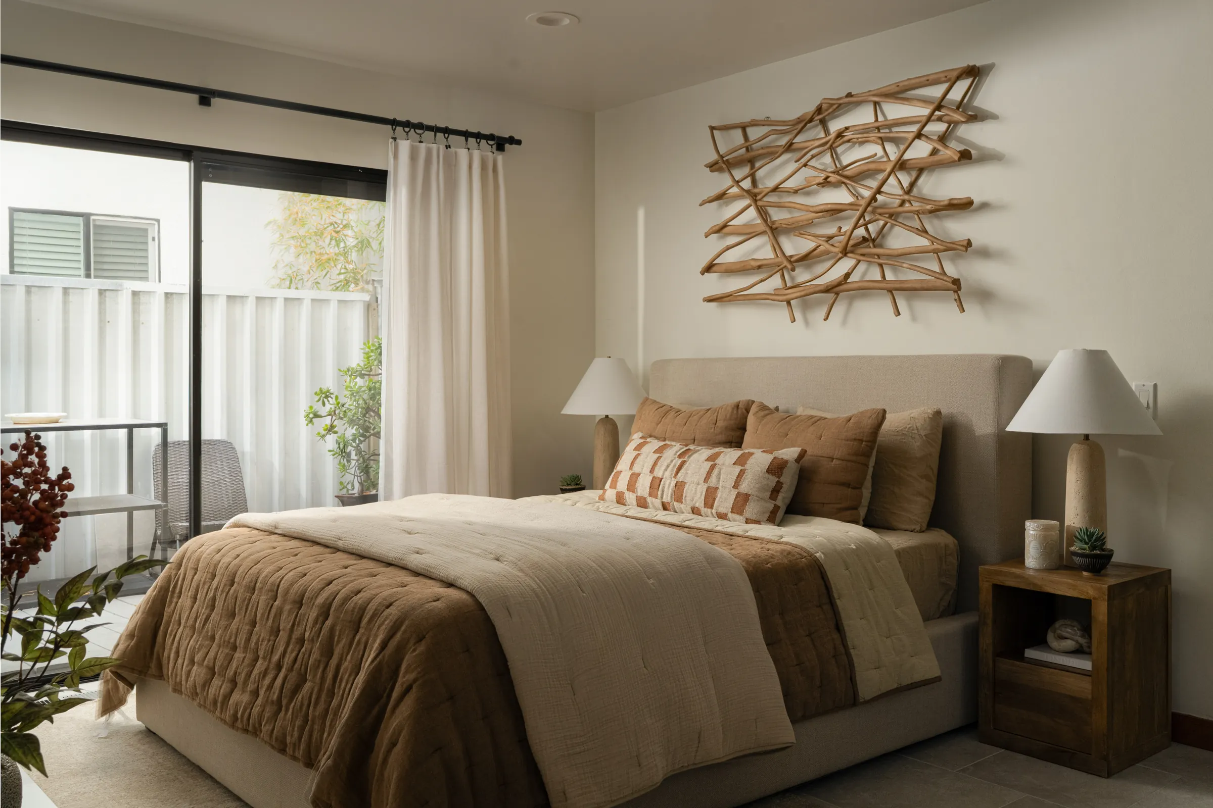 A contemporary house behind a black slatted fence with mature palms, and its interiors: a pale living room, an open kitchen and a detail of a patterned rug against leather. Frame 13 of 23.
