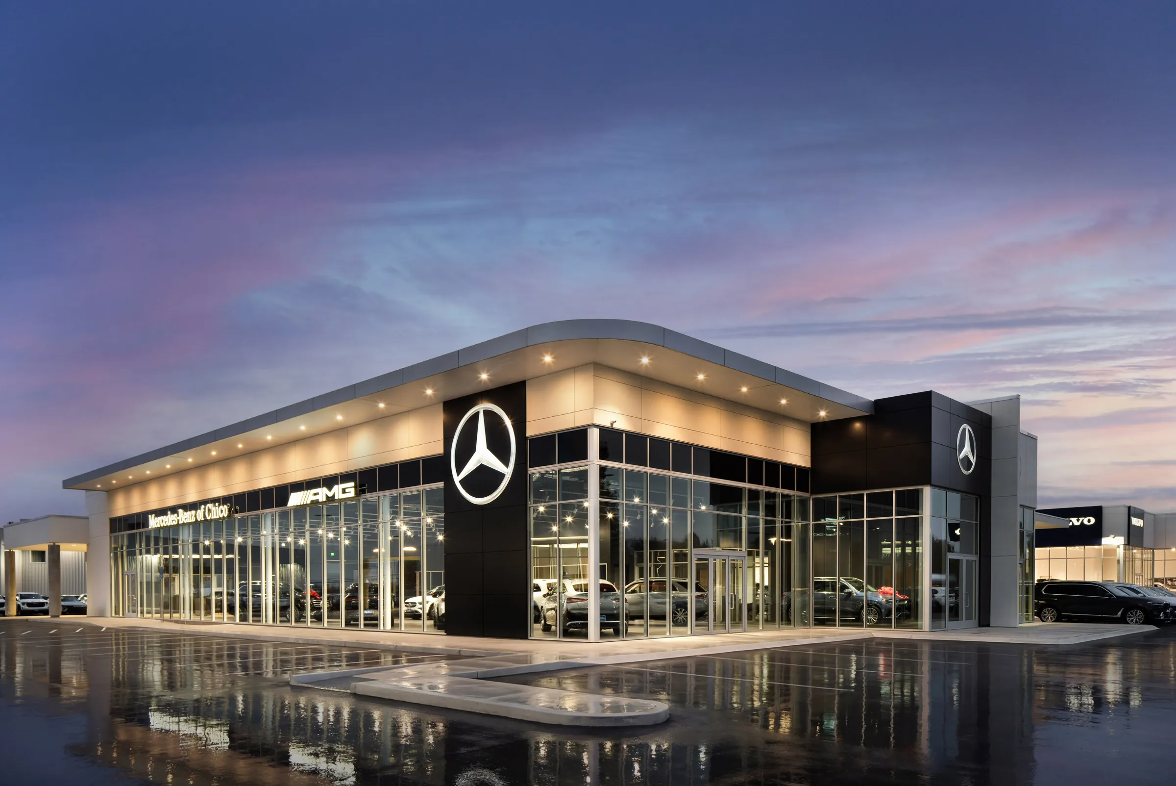 Automotive dealership exteriors at dusk and the showroom interiors behind them. Frame 2 of 6.