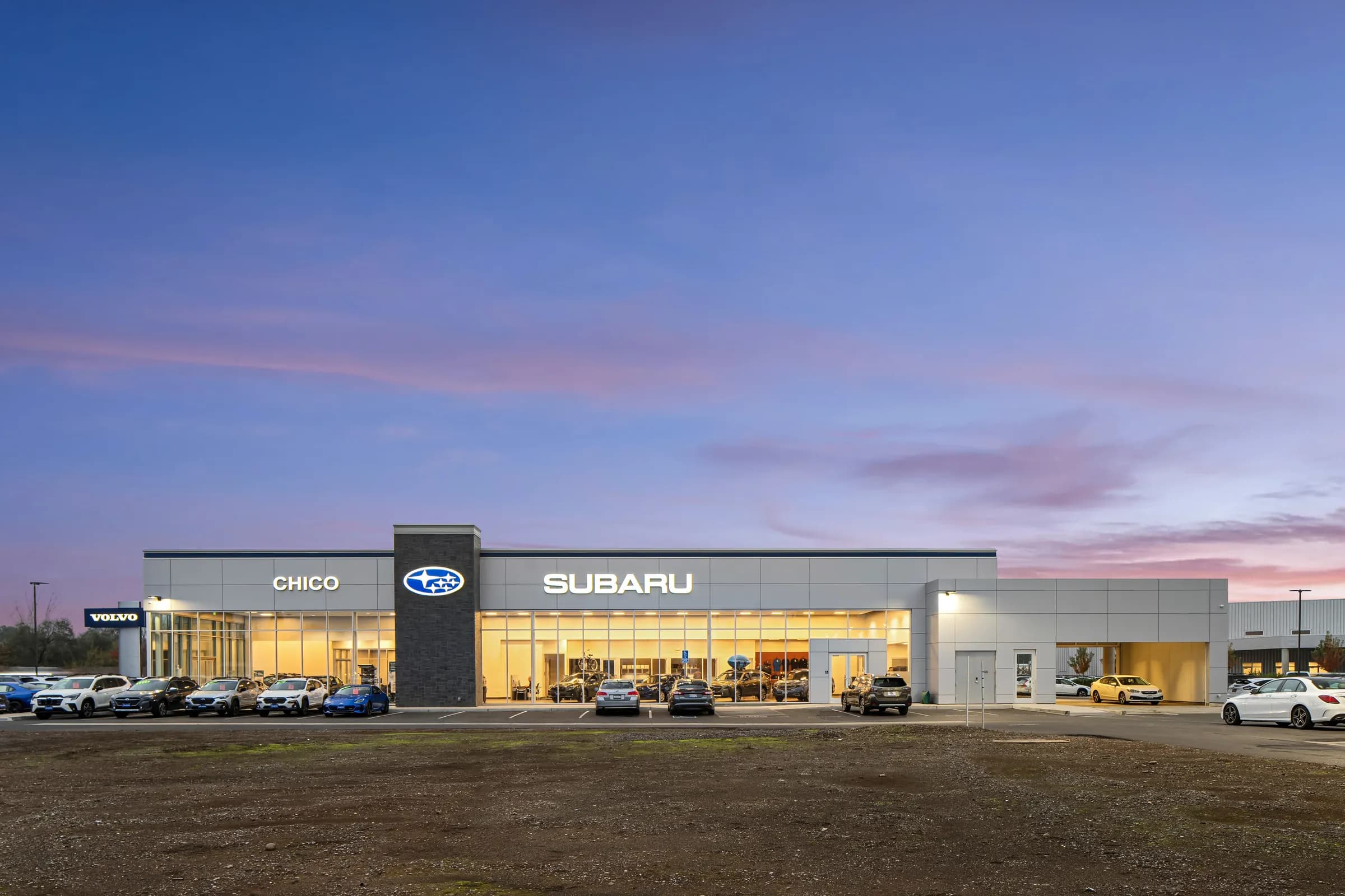Automotive dealership exteriors at dusk and the showroom interiors behind them. Frame 4 of 6.