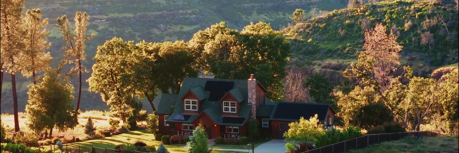 A hillside property at golden hour, the house seen from across the valley.